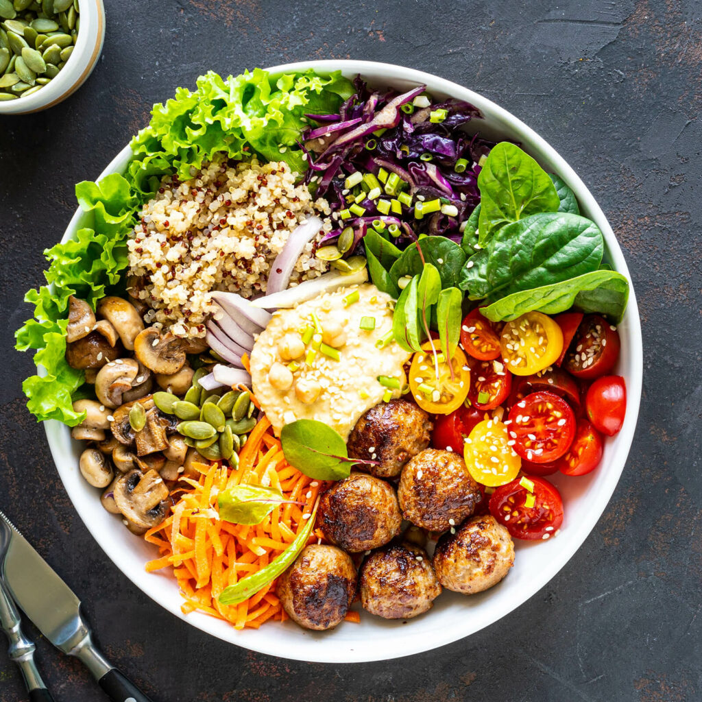 Tomatoes, mushrooms, quinoa, lettuce, spinach, and rice in vegan bowl